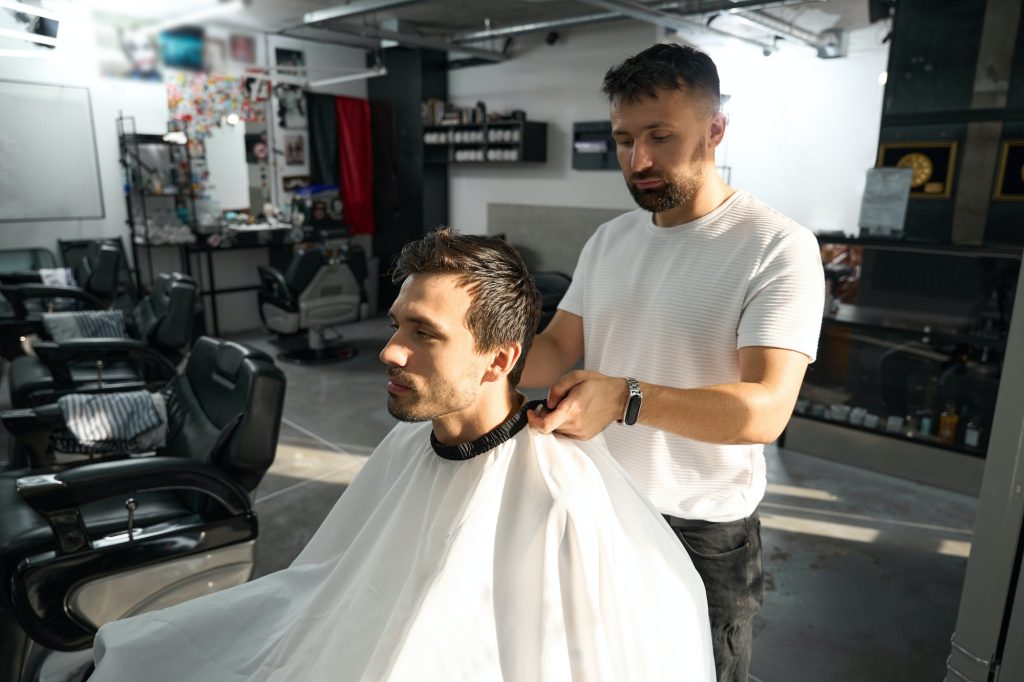 Professional barber taking care of man in haridresser chair